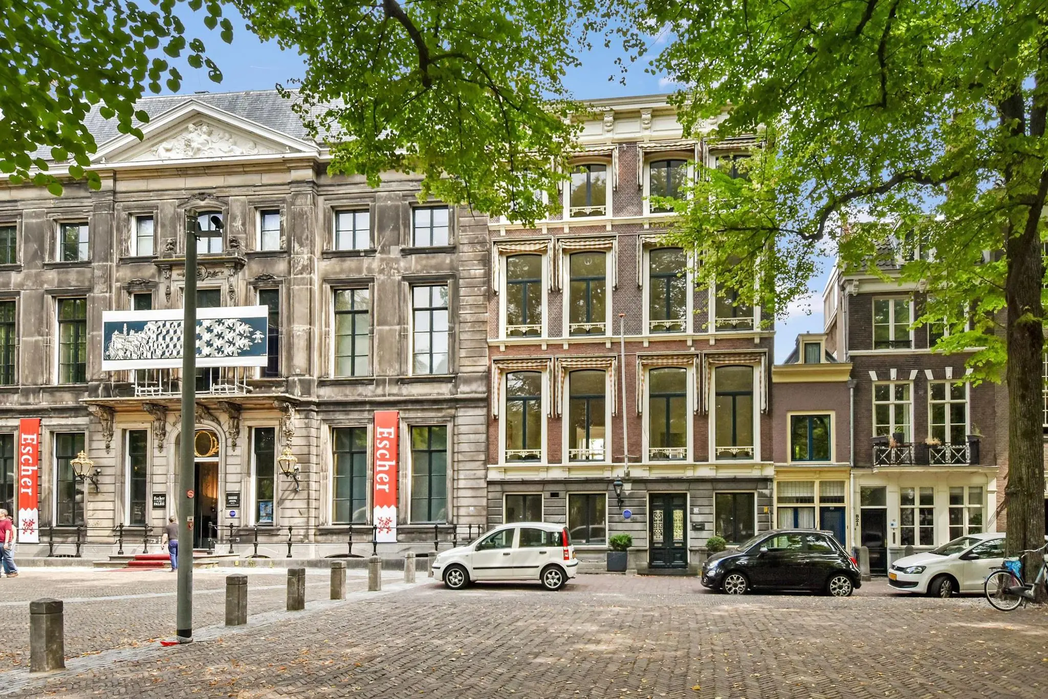 Voorgevel van het Escher Museum aan het Lange Voorhout in Den Haag, omringd door klassieke panden en bomen.